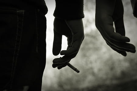 person holding cigarette grayscale photo