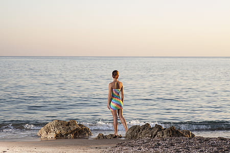 woman standing and facing body of water