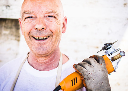 man holding yellow power tool smiling for photo