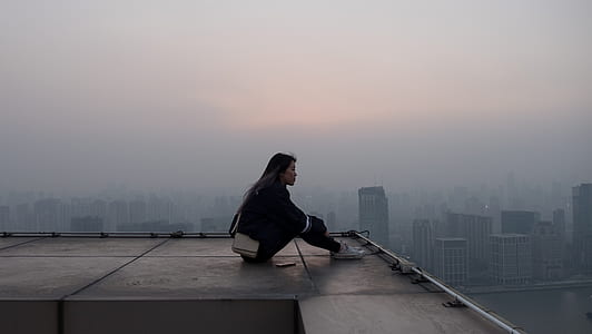 woman in black jacket and pants sitting on roof top