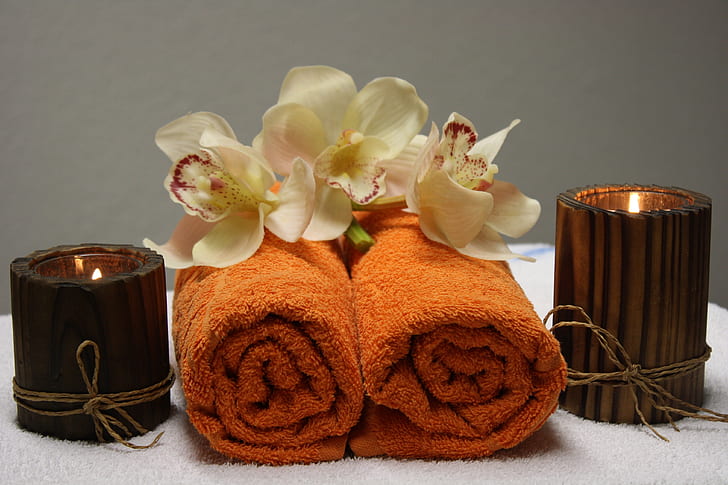two orange towels beside brown votive candles