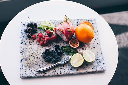 blackberries, strawberries, pomegranate and slice orange fruits on grey platter