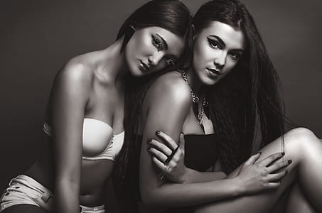 grayscale photo of woman in white padded bra leaning on shoulder of another woman