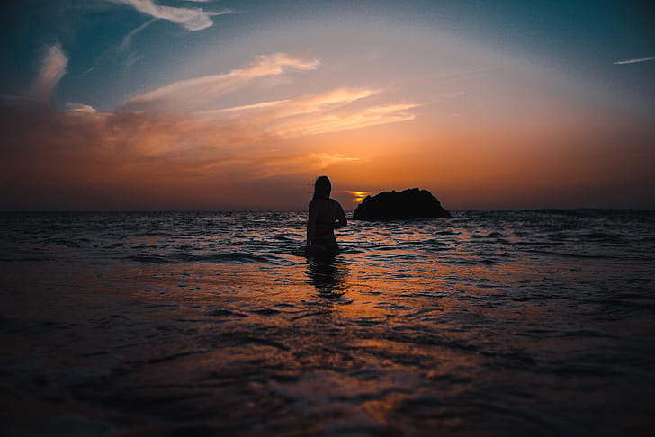 Silhouette of Woman On Ocean During Sunset