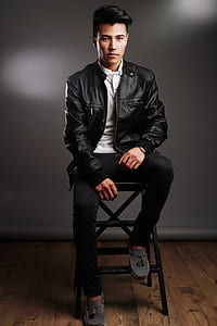 man wearing black leather zip-up jacket and pants sitting on stool