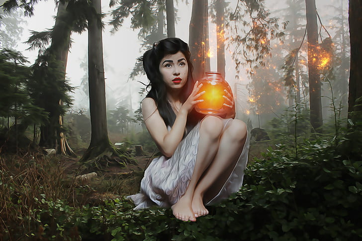 woman holding glowing jar sitting in forest