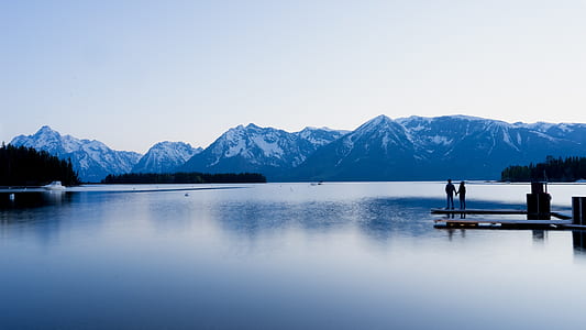 landscape photography of 2 person standing on dock during daytime