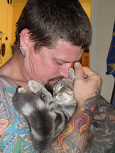 man hugging two brown tabby cats