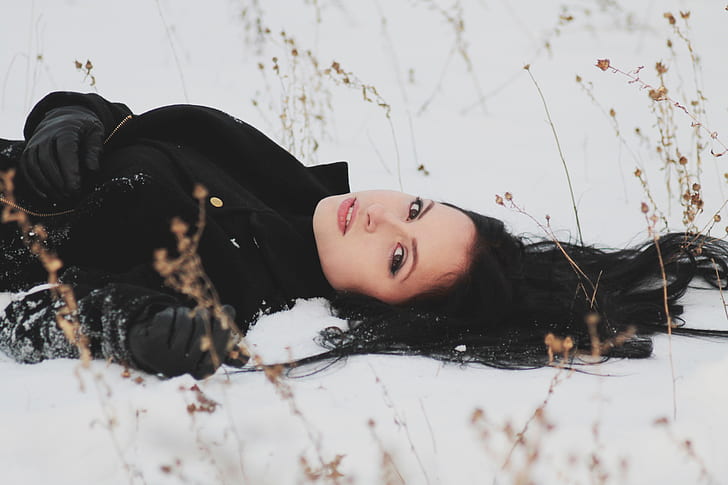 woman wearing black coat laying on snow field