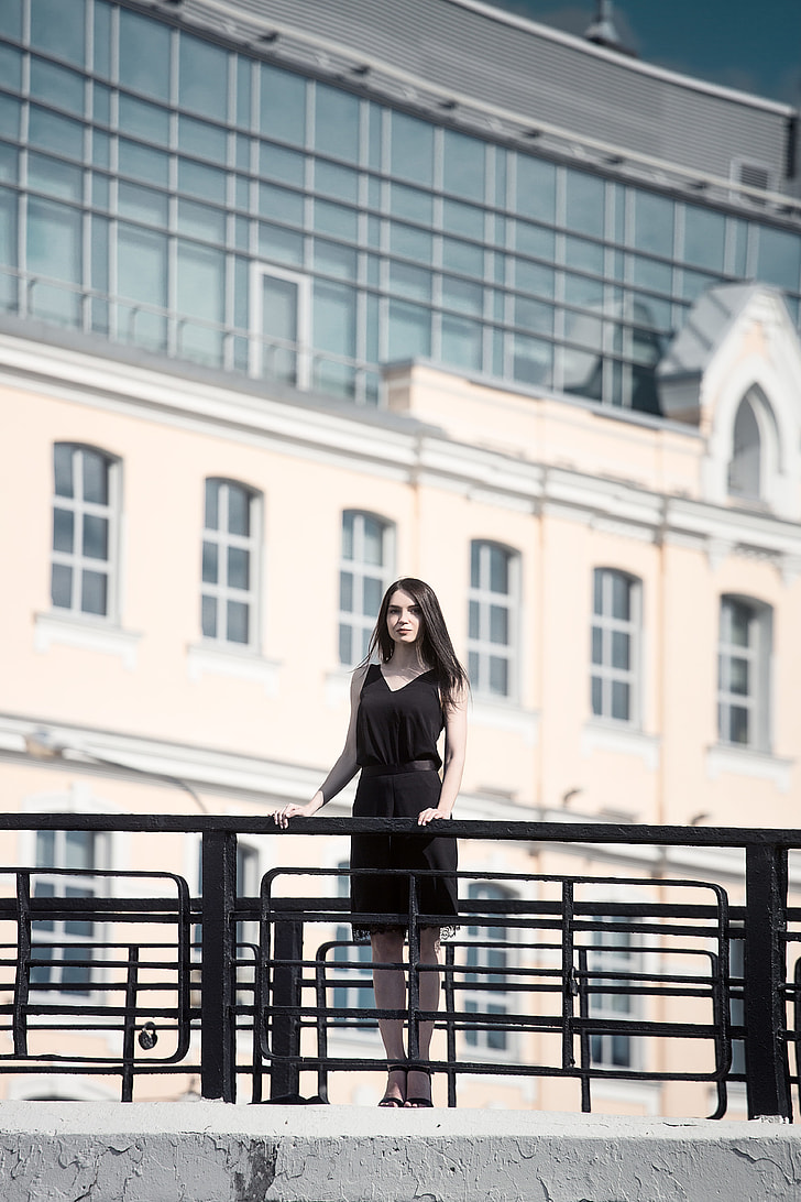 woman wearing black sleeveless dress on concrete bridge