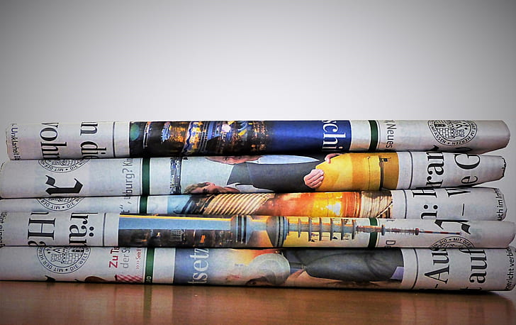 several newspapers on top of brown wooden surface