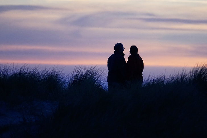 silhouette of two person on grass field