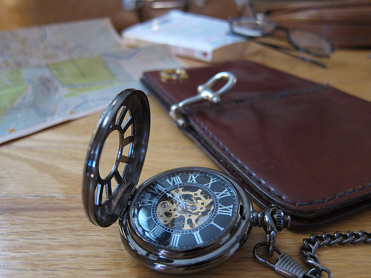 pocket watch beside brown leather wallet