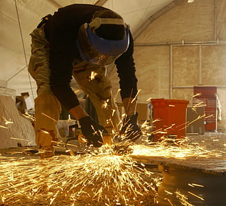 man holding welding rod wearing blue welding helmet