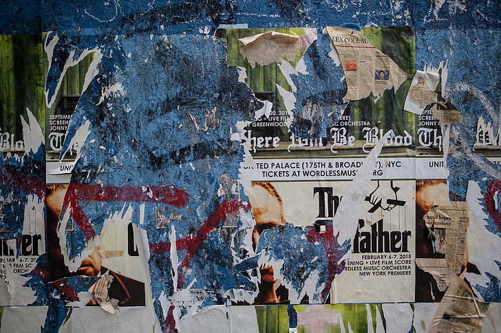 Wide angle shot of torn flyers and posters on a wall in Brooklyn, New York City
