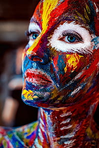 macro photo of multicolored face painted blue-eyed woman