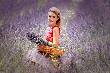 woman in red lace sleeveless top carrying basket full of purple petaled flowers