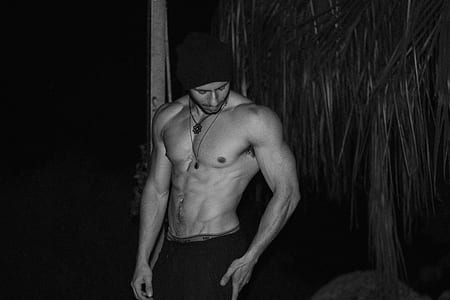 grayscale photo of topless man wearing black knit hat