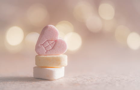 heart-shaped pink candy on top of yellow and white candies