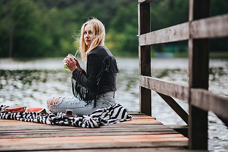 Blonde woman having a healthy snack at the wooden pier