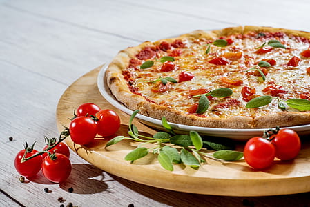 pizza with green leaves on brown wooden plate