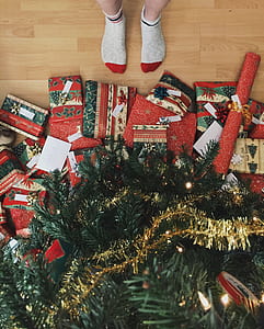 person standing infront of Christmas tree with gifts