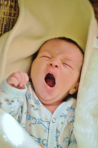baby wearing onesie yawning with blanket