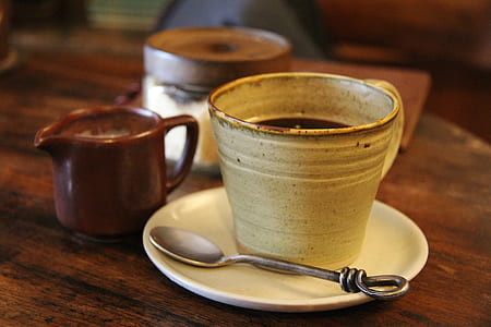 black liquid filled mug with saucer and teaspoon