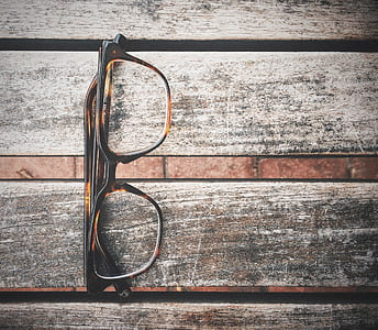 black and brown framed eyeglasses on gray and brown wooden surface