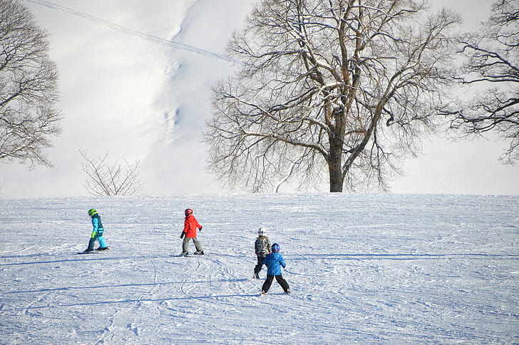 four children playing on snow at daytime
