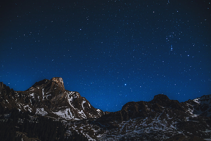 Snow-covered mountains at night with stars in sky