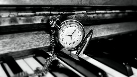 round white and silver-colored pocket watch on top of piano