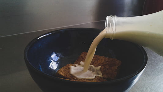 Milk Being Poured in Blue Ceramic Bowl With Cookies