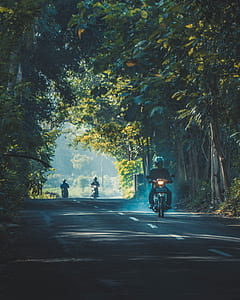 three people riding motorcycle in road