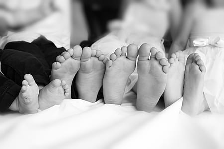 grayscale photography of four children's feet