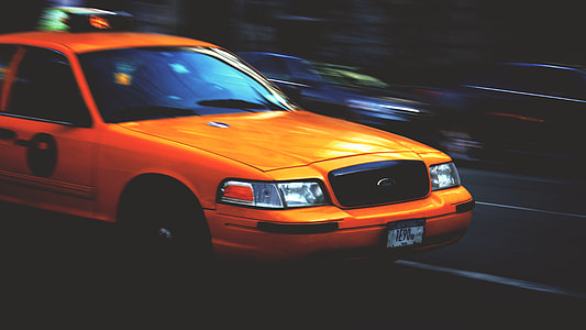 timelapse photography of orange car on black asphalt pavement