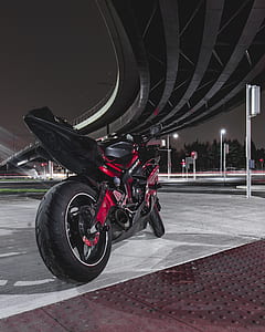 red and black sports bike parked under bridge during night