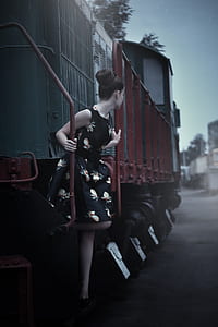 woman in black and brown floral sleeveless mini dress on red and green locomotive train