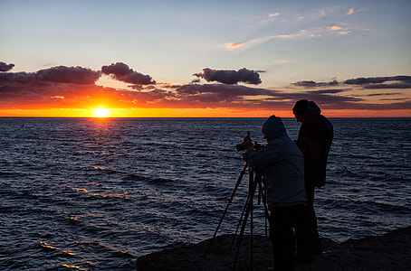Two photographers silhouetted against the setting sun. Jurassic Coast, Dorset, England
