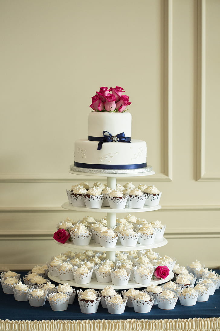 2-tier cake on top of round 4-tier cupcake rack with cupcakes