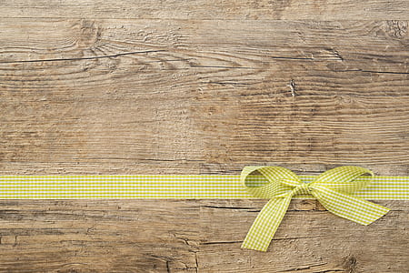 yellow and white plaid ribbon lace on brown wooden surface