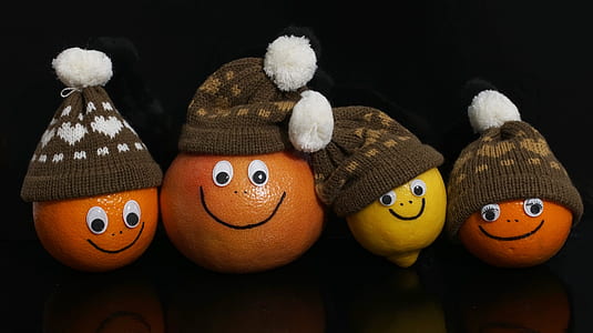 three orange citrus fruit and one lemon wearing hats decors