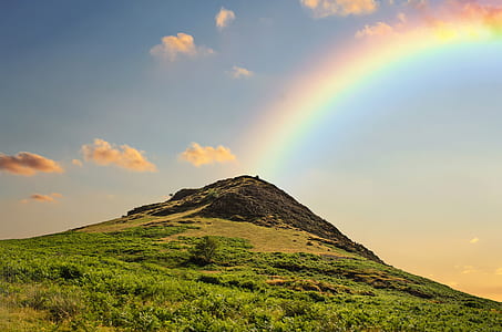 green and brown mountain with rainbow at daytime