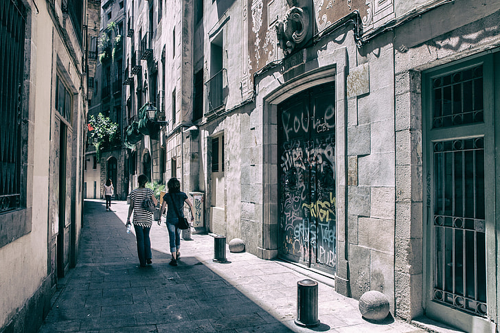 A couple of people walk through the streets of the Gothic Quarter in Barcelona, Spain