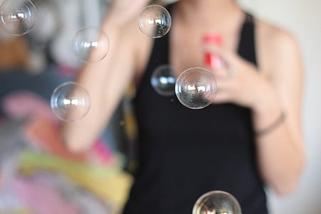 woman wearing black tank top with blowing bubbles