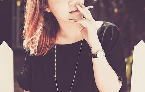 woman in black boat-neck top holding a cigarette stick