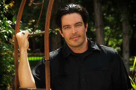 man wearing black collared shirt holding on brown metal bar during daytime