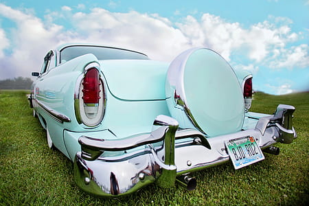 photo of vintage teal car parked on green grass field