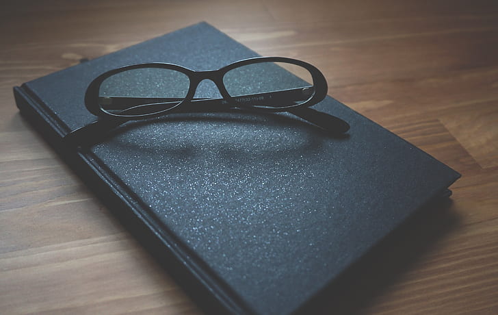 black framed eyeglasses with hardbound book