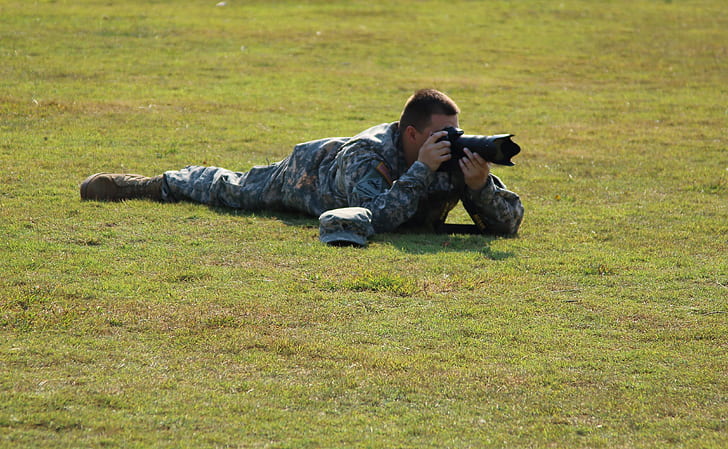 Military Crouching on Green Grass Using Dslr Camera during Daytime